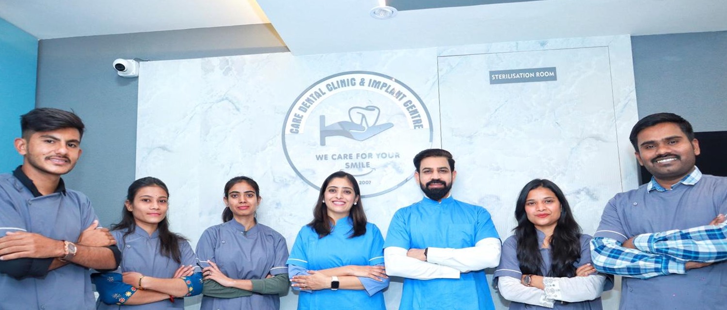 A diverse group of Dentist posing in front of a white wall, in Care dental Clinic.