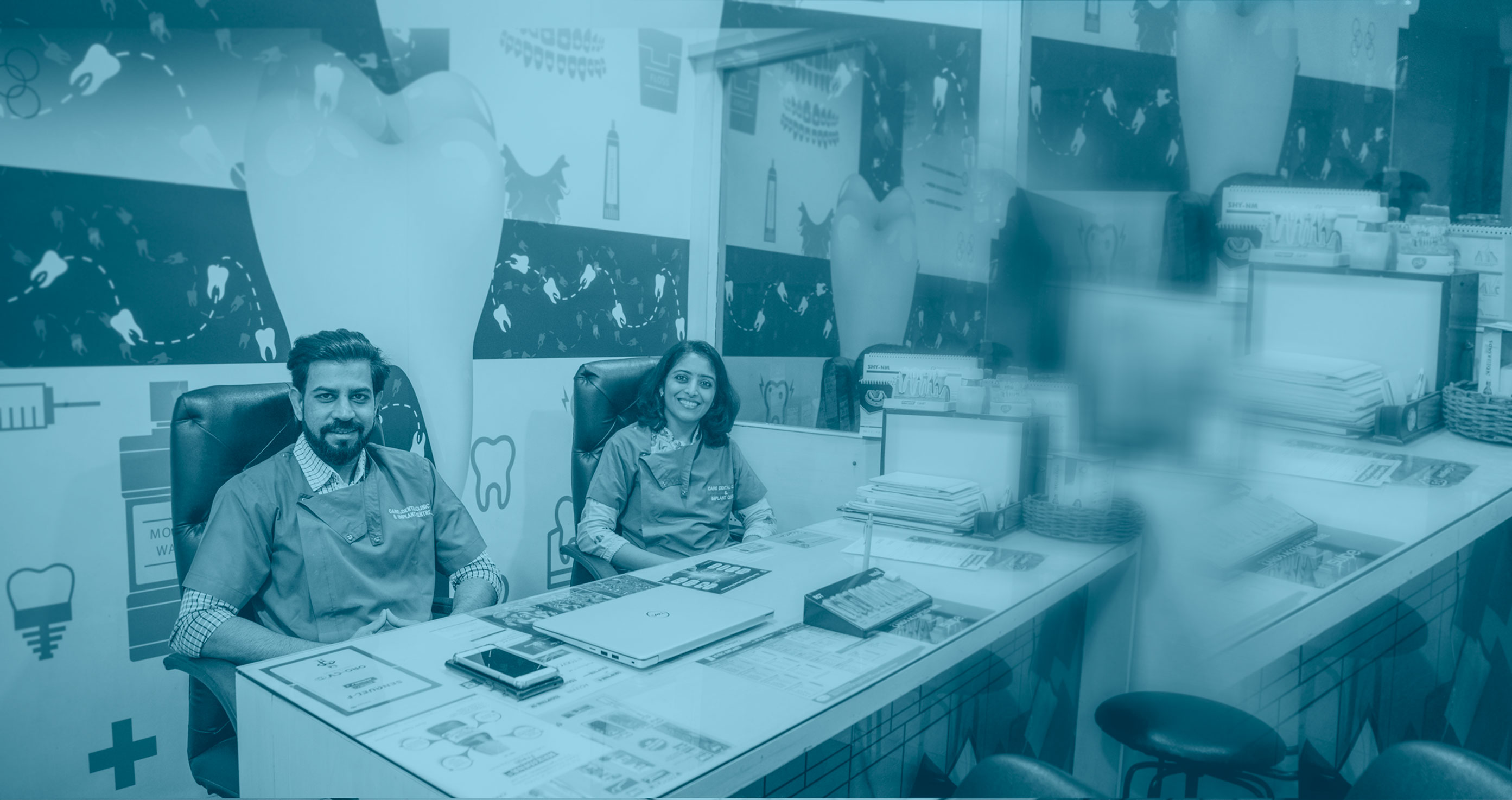 Dr. Gagan Jaiswal. and Dr Shraddha Jaiswal sit at a desk at Care Dental Clinic