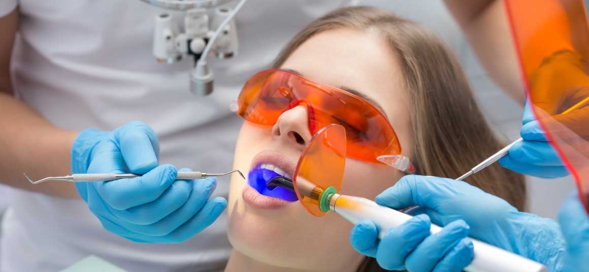 A woman getting her teeth cleaned by a dentist with laser dentistry