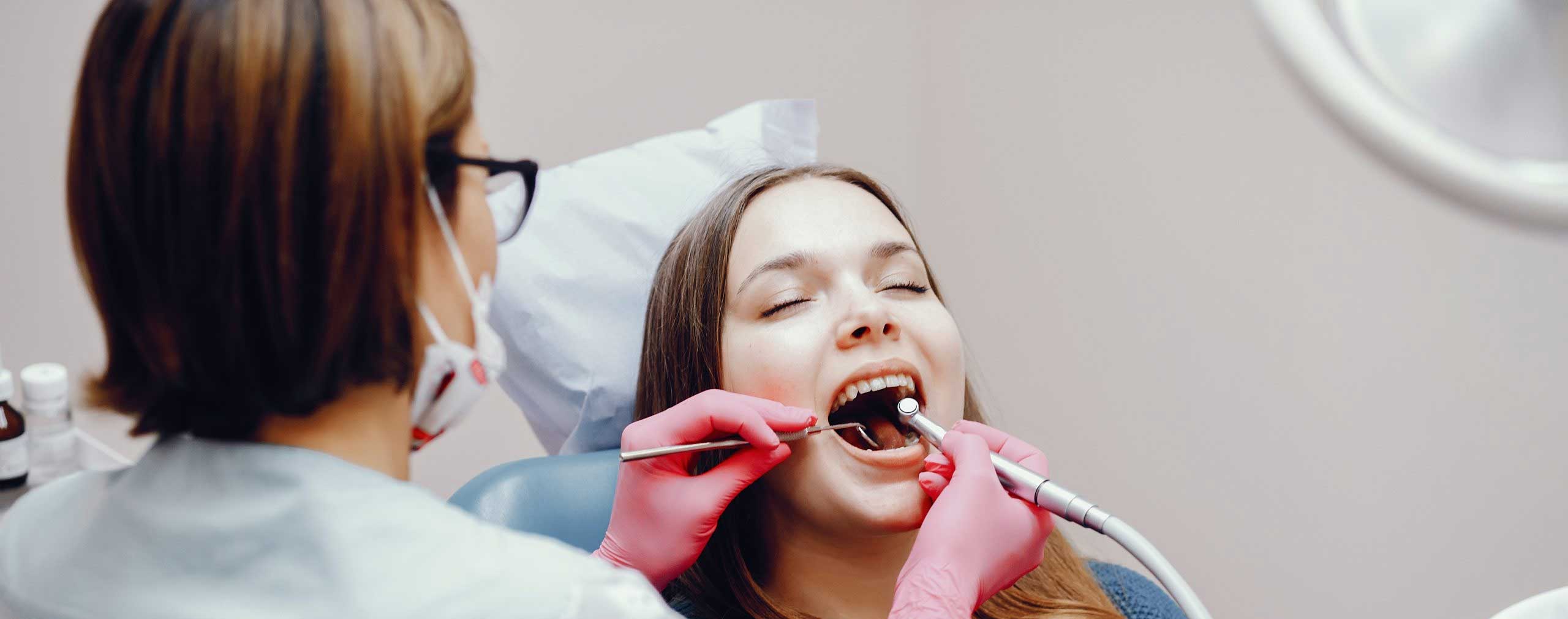 A woman getting her teeth cleaned by a dentist, ensuring her oral health and a bright smile with painless dental treatment.